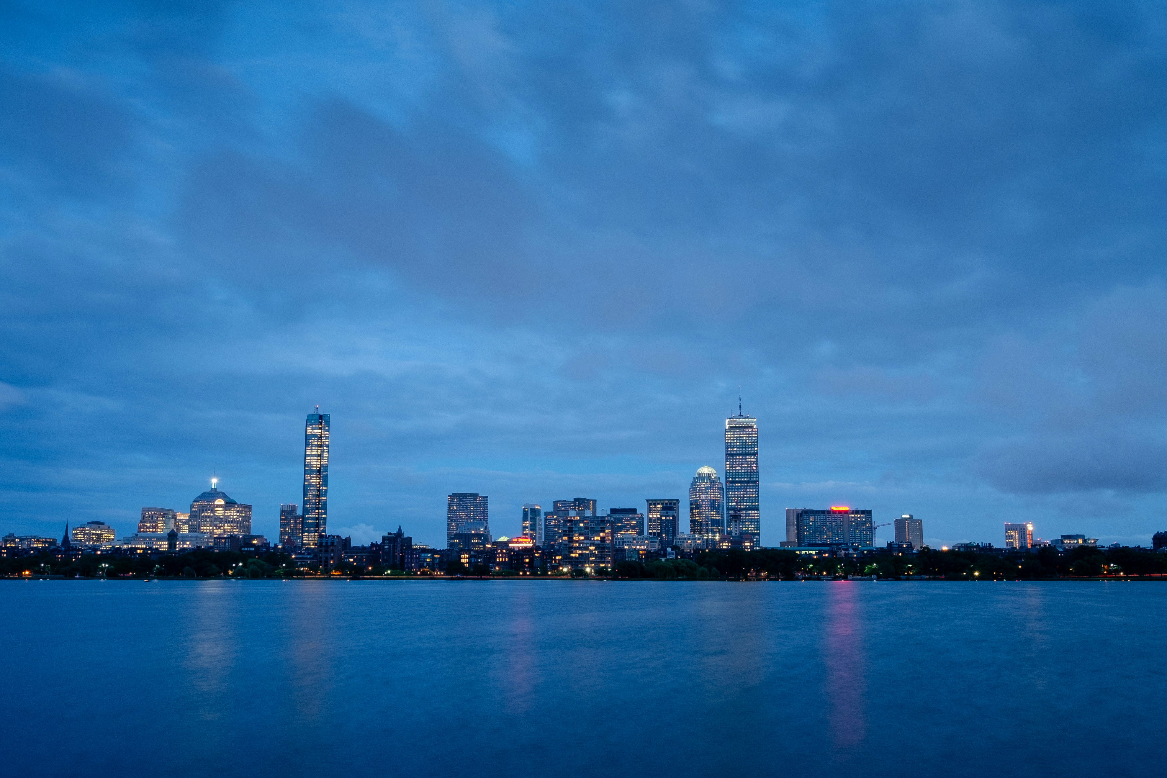 city skyline across body of water during night time